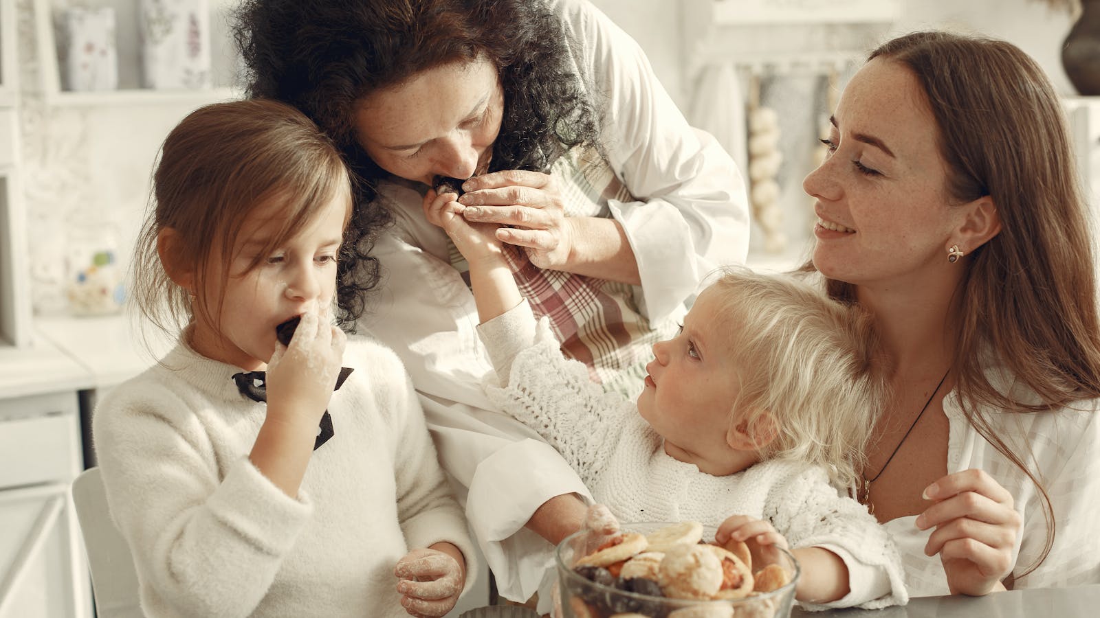 Three generations of women sharing a moment in a sunlit kitchen